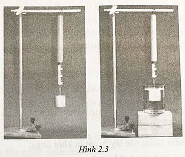 Treo một quả cân vào lực kế thì lực kế chỉ 2,5 N. Vẫn treo quả cân đó nhưng nhúng ngập nó vào nước (hình 2.3) thì thấy lực kế chỉ 1,9 N. Sự thay đổi số